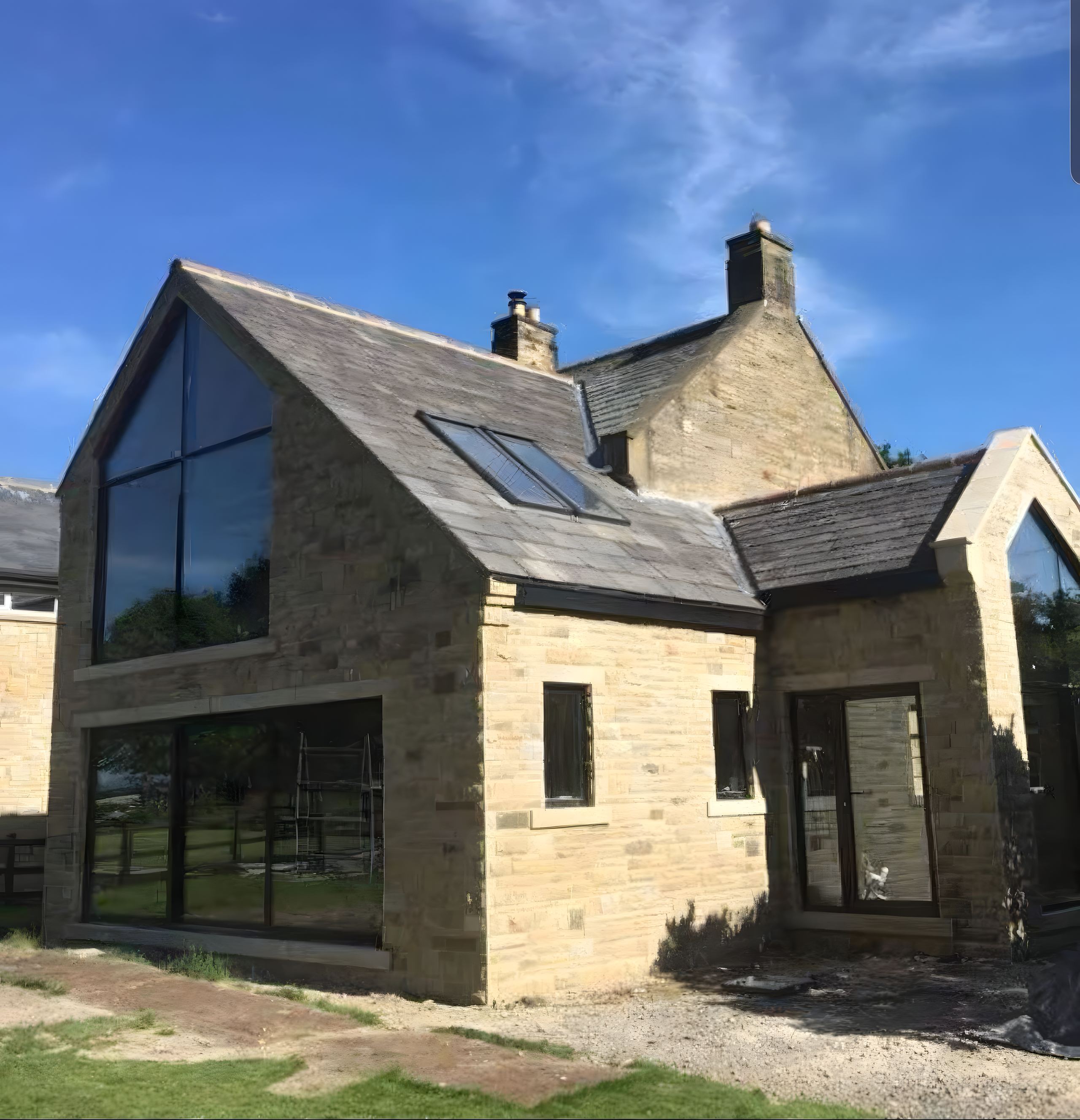 Finished two-storey stone-matched extension, glazed gables against the original house, in daylight