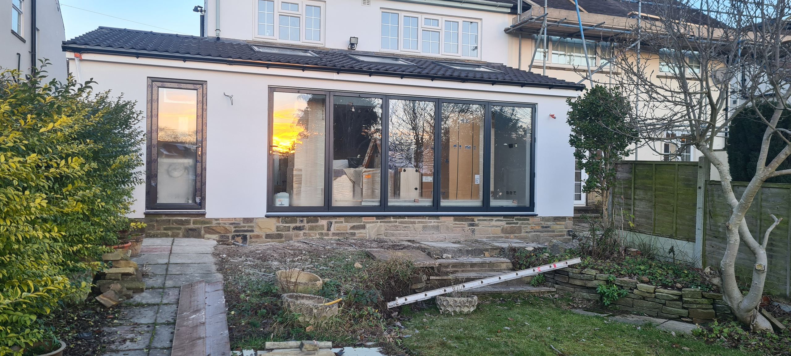finished single-storey rear extension, bifolds and rooflights, low winter sun in the glass