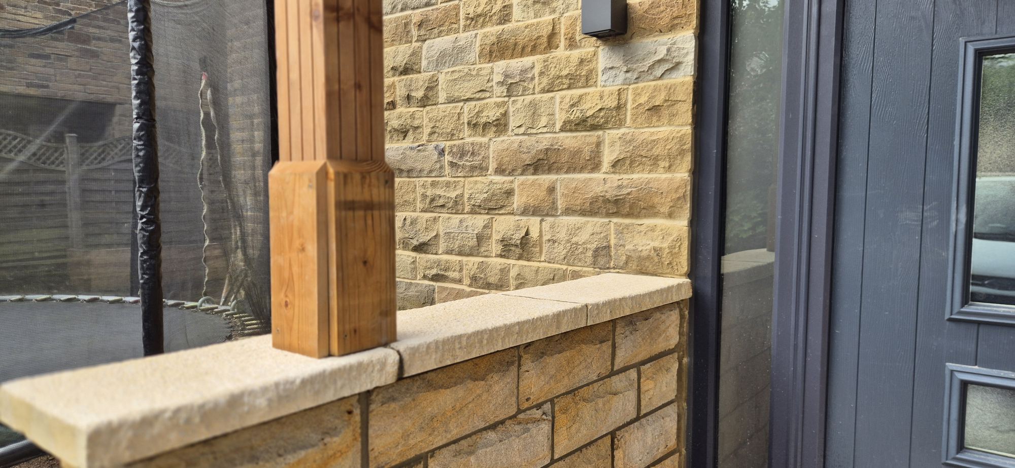 timber porch post on a coursed stone dwarf wall with a dressed coping