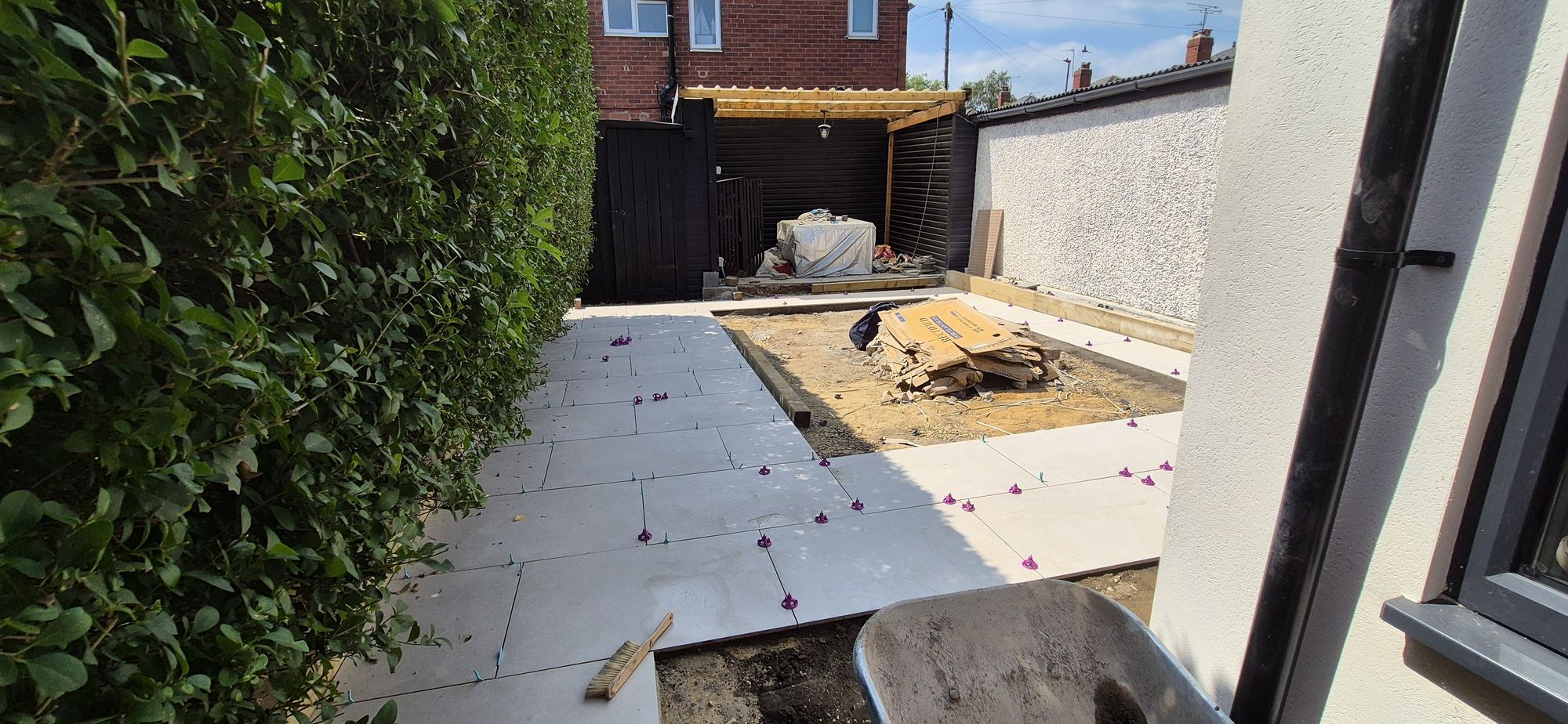 Large-format grey porcelain being laid on levelling spacers down the side of a house in Starbeck, Harrogate