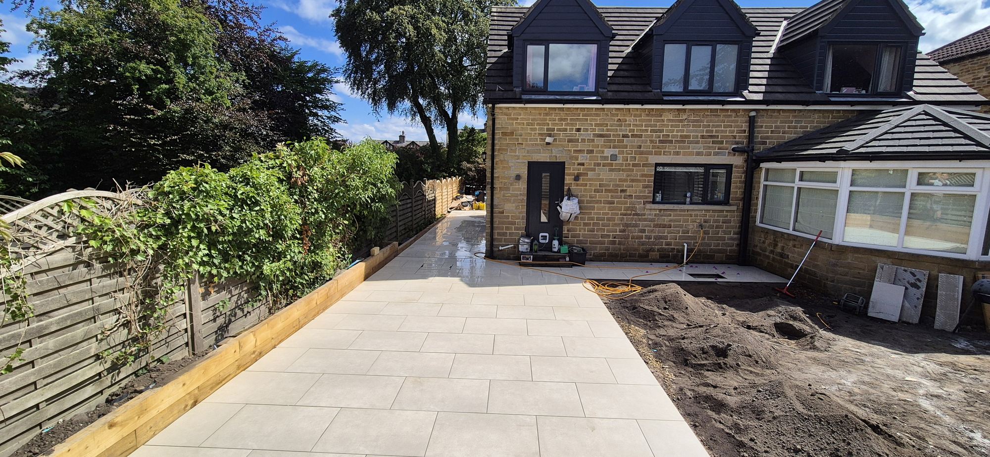 cream large-format porcelain patio in the sun, running to the stone house