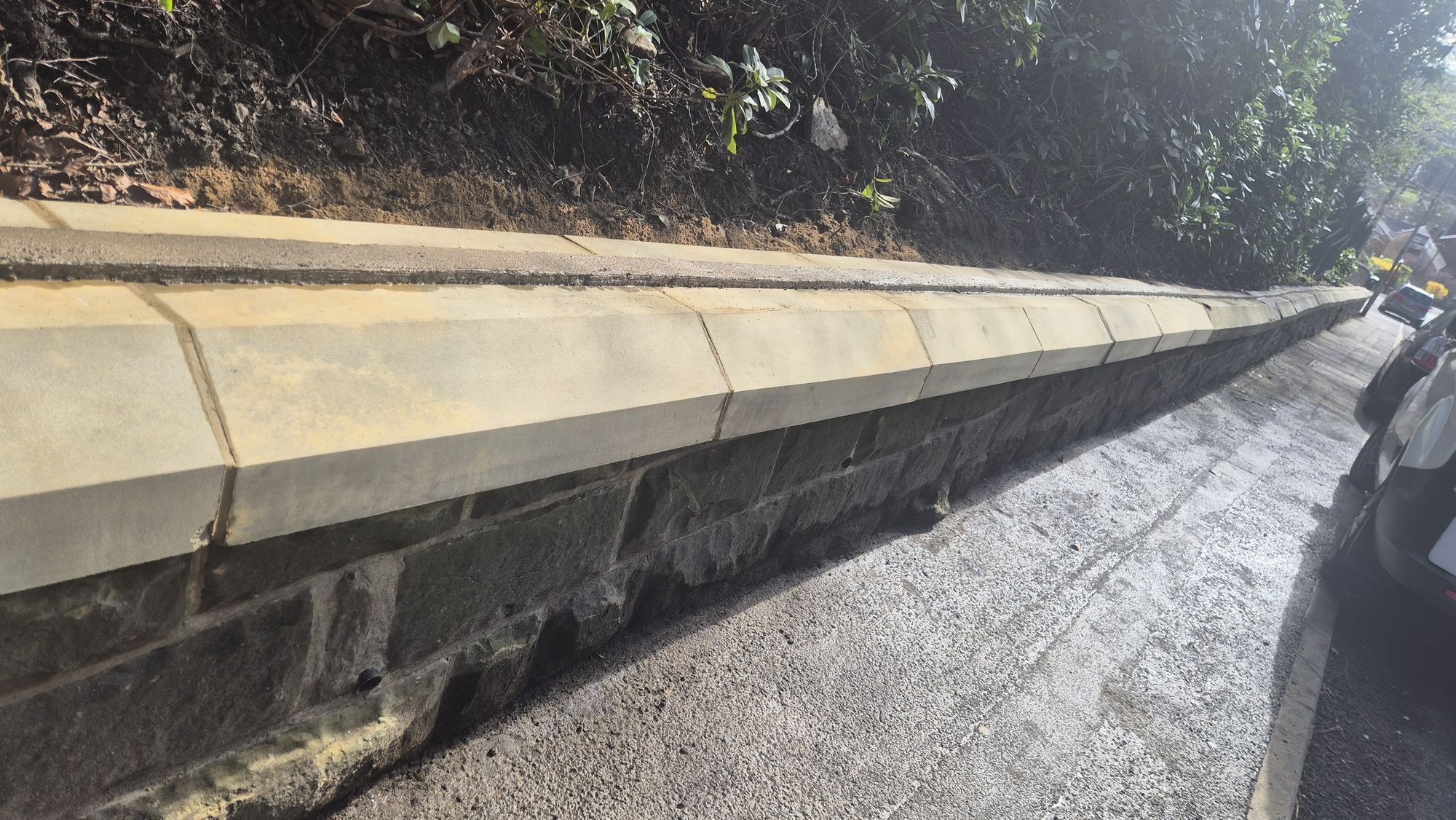 old salvaged stone in a rebuilt wall under new sandstone coping
