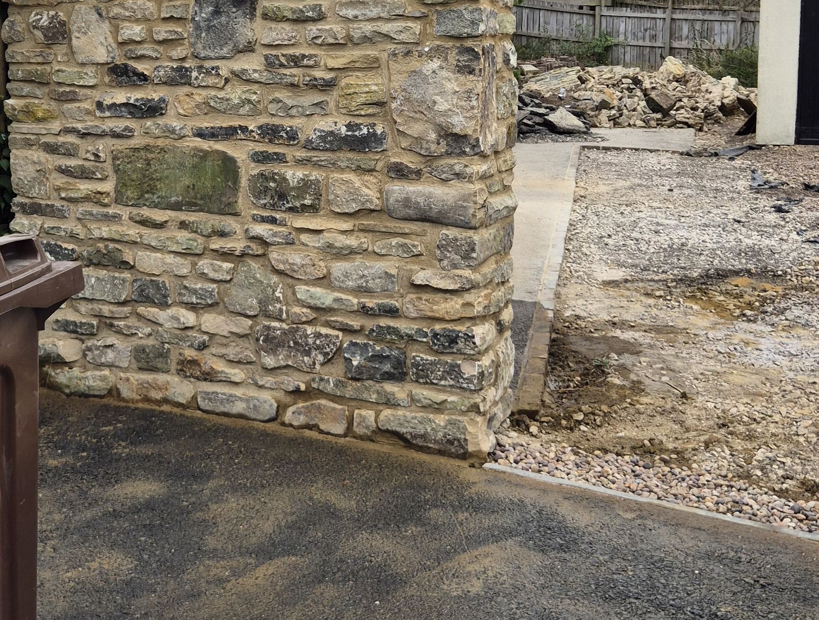 a finished run of natural stone boundary wall with its coping, beside the drive