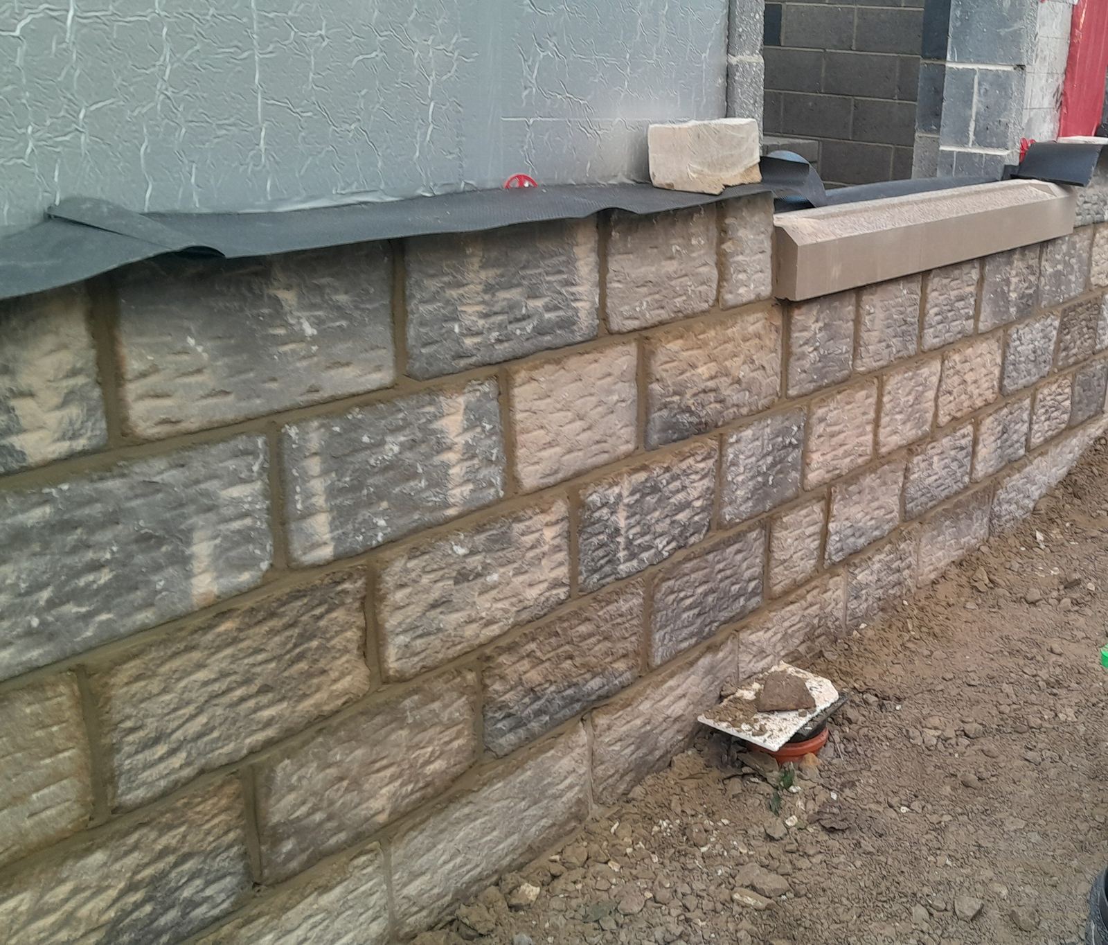 new sandstone coping bedded on top of the levelled wall