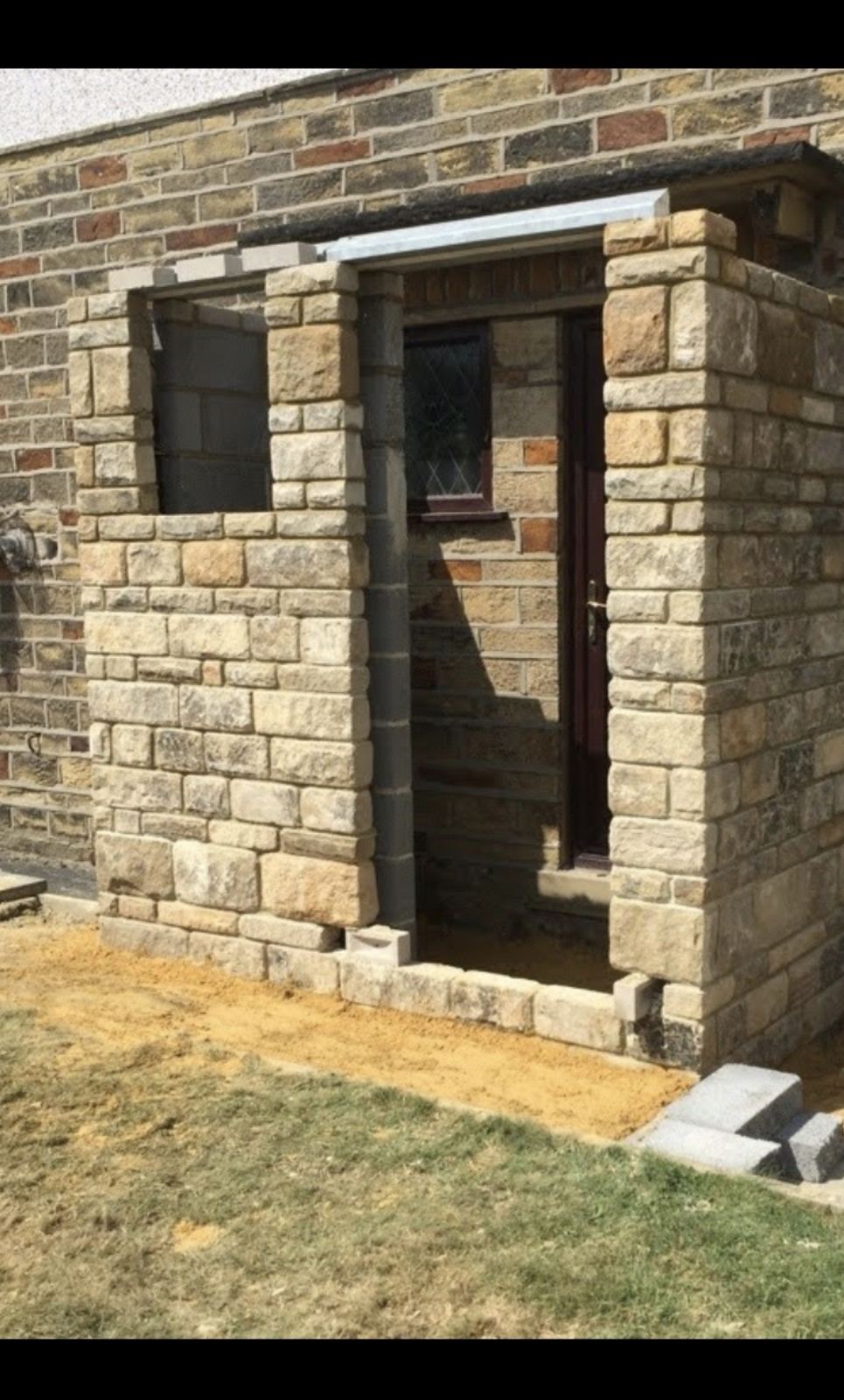 a stone porch going up, walls and pillars coursed, ready for its canopy