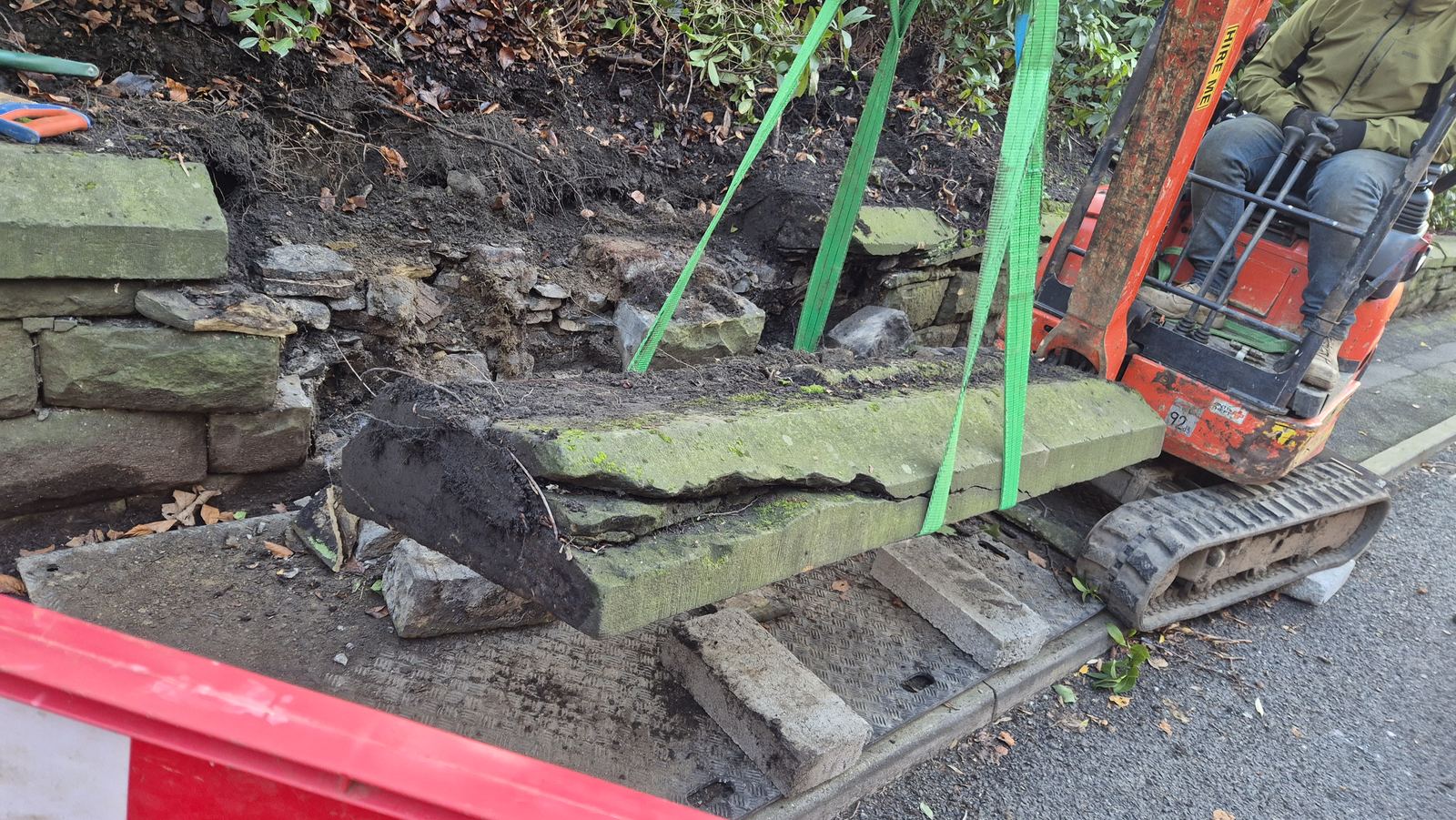 old leaning garden wall part taken down, salvaged stone stacked